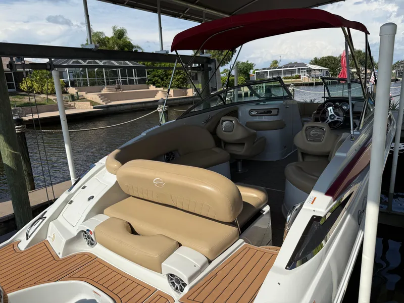 Slide: The Image of 2019 Crownline Eclipse E255 XS boat with tan seating and red canopy docked by a canal. - 4