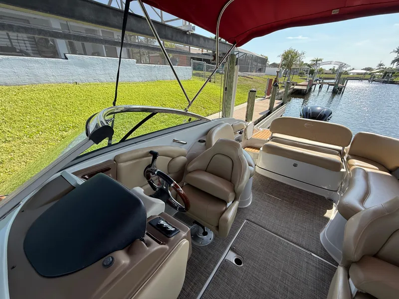 Slide: The Image of 2019 Crownline Eclipse E255 XS boat interior with helm, seating, and waterfront view. - 6
