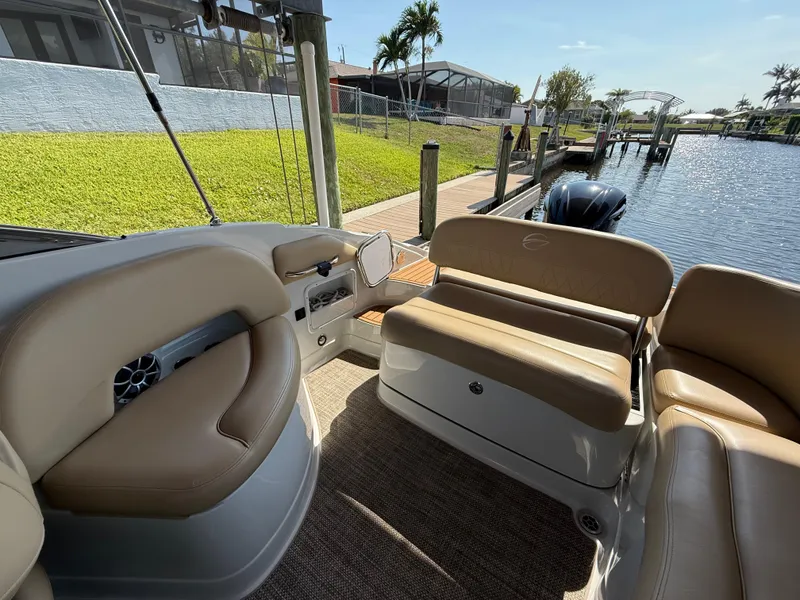Slide: The Image of 2019 Crownline Eclipse E255 XS boat interior with beige seating by a dock. - 8