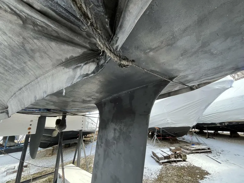 Slide: The Image of 1996 Farr 30 sailboat keel and hull in dry dock, surrounded by other boats. - 4