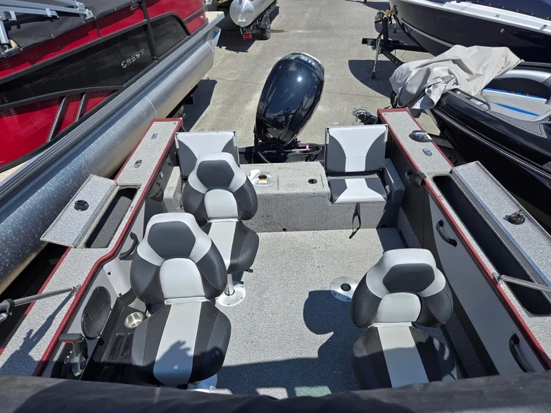 Slide: The Image of 2022 Alumacraft Trophy 185 boat interior with four seats and motor, docked among other boats. - 12