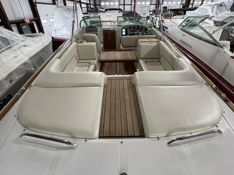Slide: The Image of 2005 Chris-Craft Corsair 28 boat interior with white seating and wooden flooring. - 10