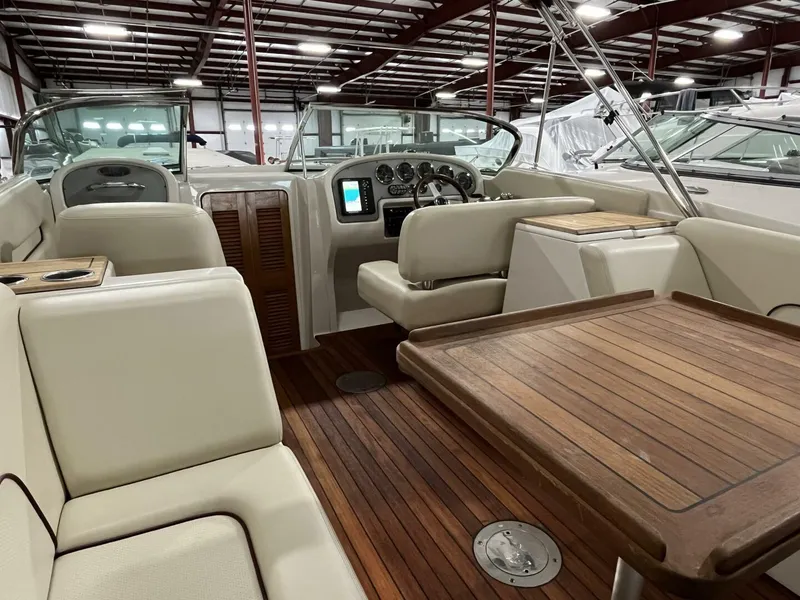 Slide: The Image of 2005 Chris-Craft Corsair 28 interior with wooden deck and beige seating in a showroom. - 12
