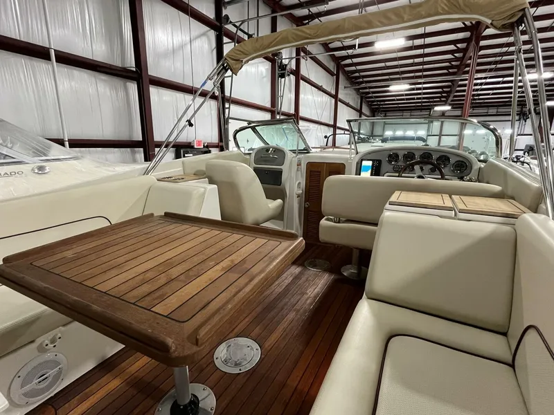 Slide: The Image of 2005 Chris-Craft Corsair 28 interior with wooden table and beige seating in a warehouse. - 14