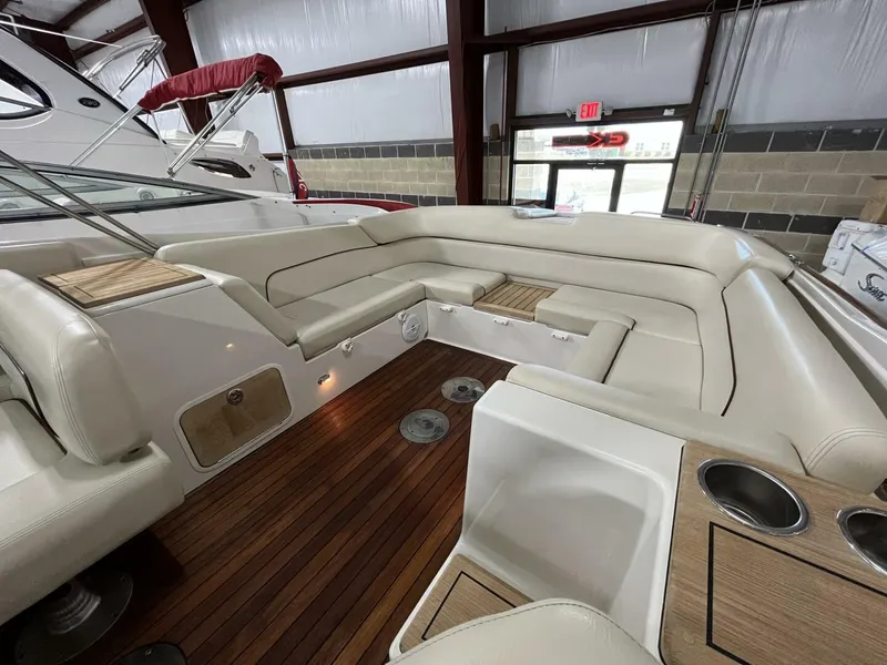 Slide: The Image of 2005 Chris-Craft Corsair 28 interior with beige seating and wooden flooring in a showroom. - 15