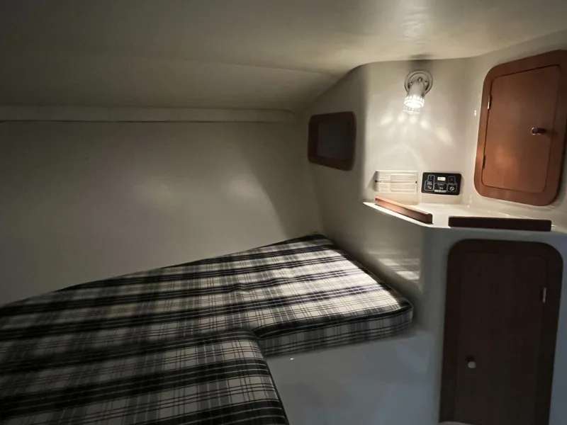 Slide: The Image of 2005 Chris-Craft Corsair 28 cabin interior with plaid bedding and wooden storage compartments. - 33