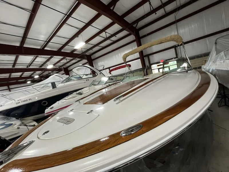 Slide: The Image of 2005 Chris-Craft Corsair 28 boat in indoor storage, showcasing sleek design and wooden accents. - 45