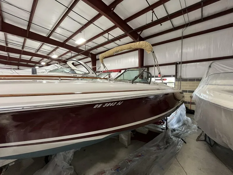 Slide: The Image of 2005 Chris-Craft Corsair 28 boat in storage, maroon hull, indoor facility. - 7