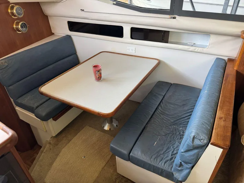 Slide: The Image of 1994 Carver 350 Aft Cabin interior with dining area, featuring blue cushioned seating and a table. - 20