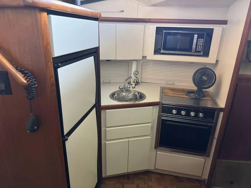 Slide: The Image of 1994 Carver 350 Aft Cabin kitchen with fridge, sink, stove, and microwave. - 22