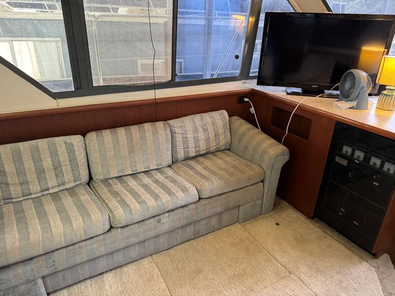 Slide: The Image of 1994 Carver 350 Aft Cabin interior with striped sofa, TV, and fan on a wooden cabinet. - 18