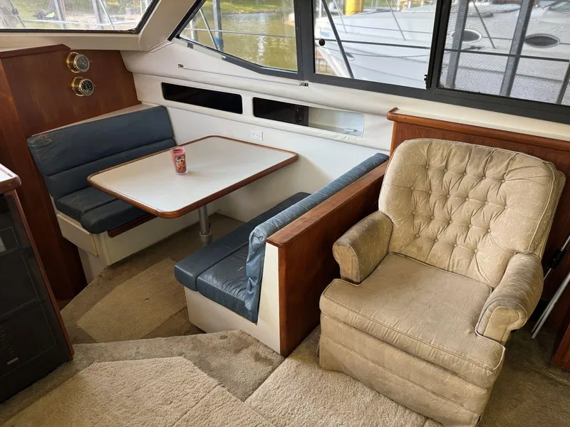 Slide: The Image of 1994 Carver 350 Aft Cabin interior with dining area and armchair, featuring a cozy layout. - 19