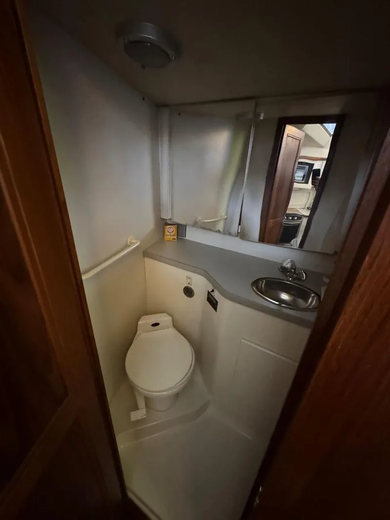 Slide: The Image of 1994 Carver 350 Aft Cabin bathroom with toilet, sink, and mirror. - 24