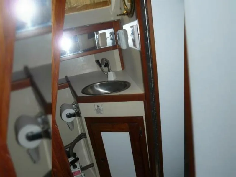 Slide: The Image of Interior of 1990 Catalina Capri 26 Wing Keel, featuring compact bathroom with sink and mirror. - 6