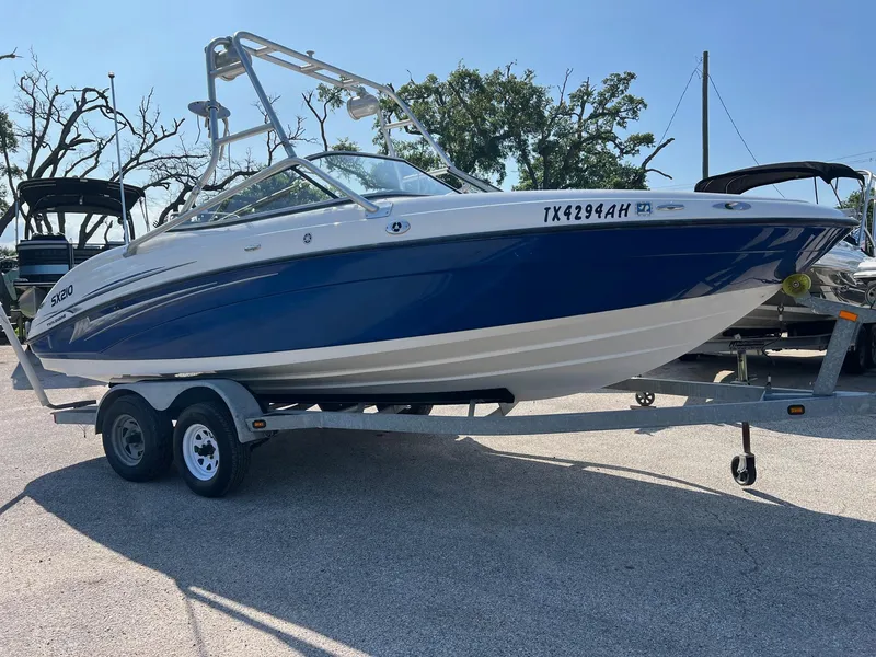 The Image of 2006 Yamaha SX210 boat on trailer, blue and white design, parked outdoors. - 0