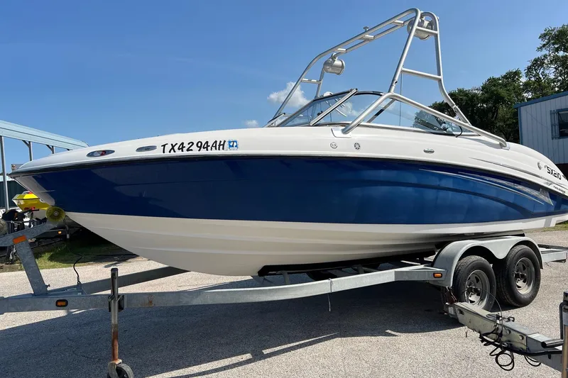 Slide: The Image of 2006 Yamaha Boats SX210 on trailer, blue and white hull, parked outdoors. - 23
