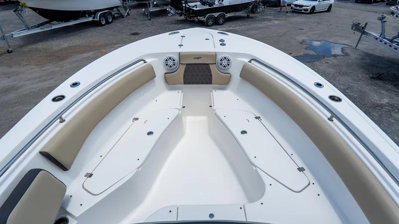 Slide: The Image of 2020 Tidewater 232 LXF boat interior with beige seating and speakers, parked on a lot. - 17