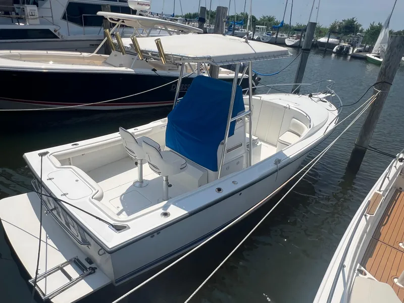 The Image of 2003 Shamrock 220 Cuddy boat docked in marina, featuring white exterior and blue cover. - 0