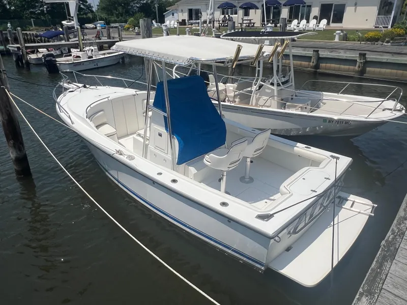 Slide: The Image of 2003 Shamrock 220 Cuddy boat docked at marina, featuring spacious deck and seating. - 1