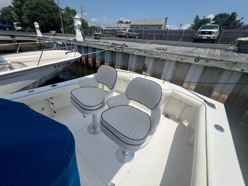 Slide: The Image of 2003 Shamrock 220 Cuddy boat with two white seats docked at a marina. - 4