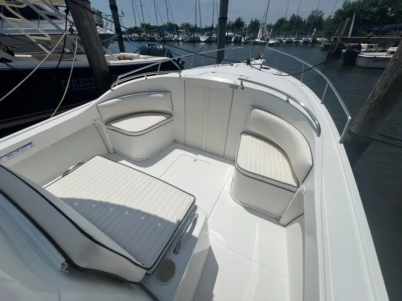 Slide: The Image of 2003 Shamrock 220 Cuddy boat interior with white cushioned seating at a marina. - 5