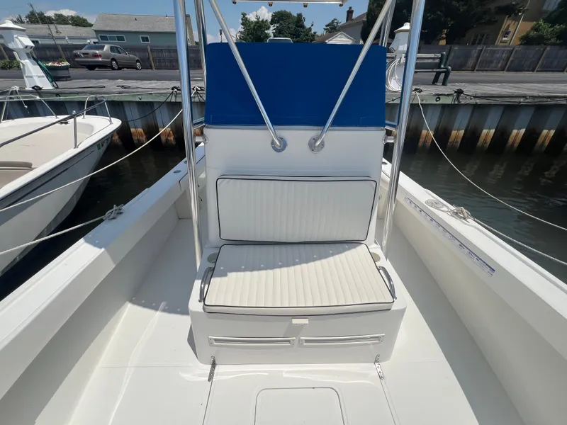 Slide: The Image of 2003 Shamrock 220 Cuddy boat interior with white seating and blue accents at dock. - 7
