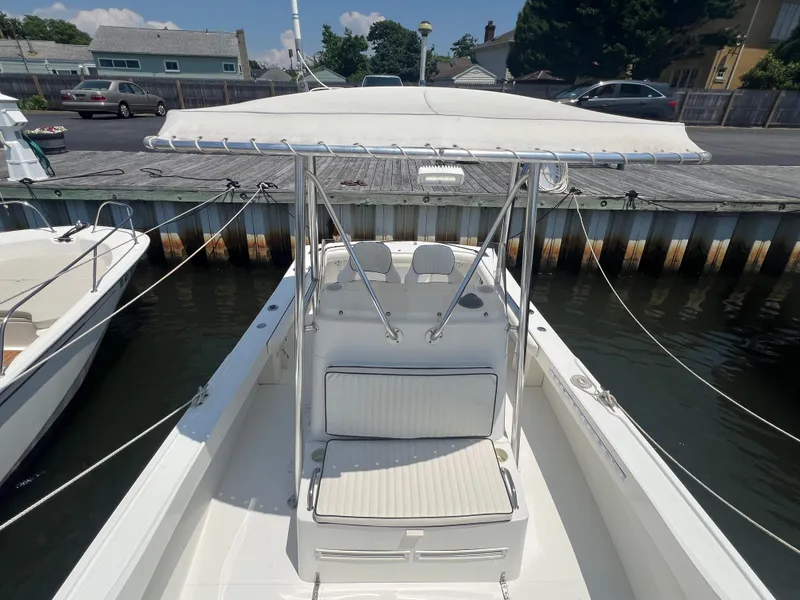 Slide: The Image of 2003 Shamrock 220 Cuddy boat docked at marina, featuring a white canopy and seating. - 8