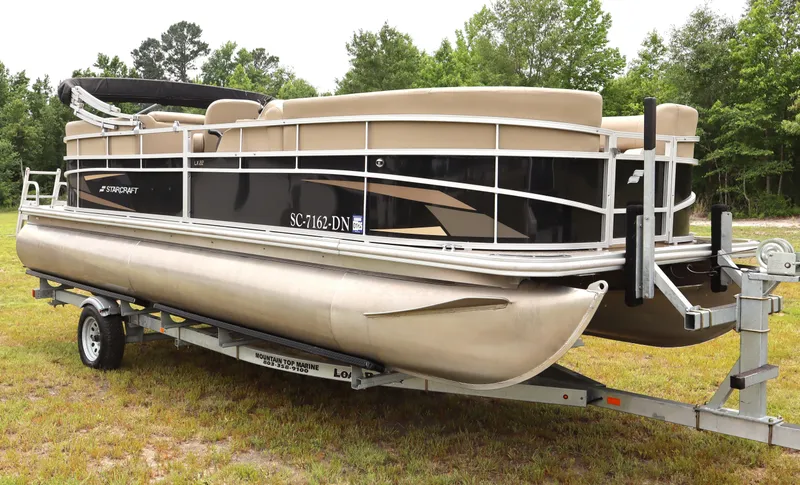 Slide: The Image of 2021 Starcraft LX 22 R pontoon boat on trailer, parked on grass. - 1