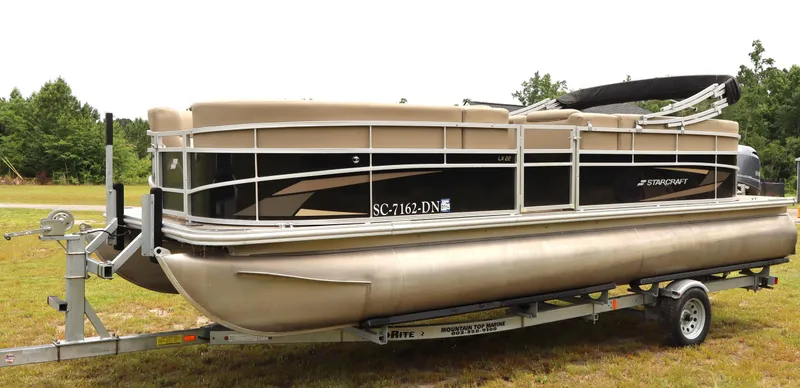 Slide: The Image of 2021 Starcraft LX 22 R pontoon boat on trailer, parked on grass. - 5