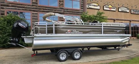 Slide: The Image of 2025 Sun Tracker SportFish 22 DLX pontoon boat on trailer outside dealership. - 2