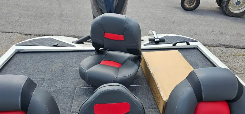 Slide: The Image of 2025 Tracker Savage 215 boat interior with black and red seats, carpeted deck, and a cardboard box. - 17