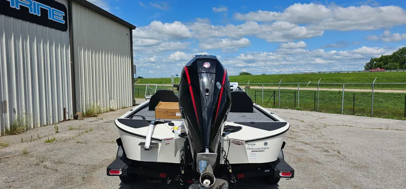 Slide: The Image of 2025 Tracker Savage 215 boat with outboard motor, parked outdoors on a sunny day. - 2