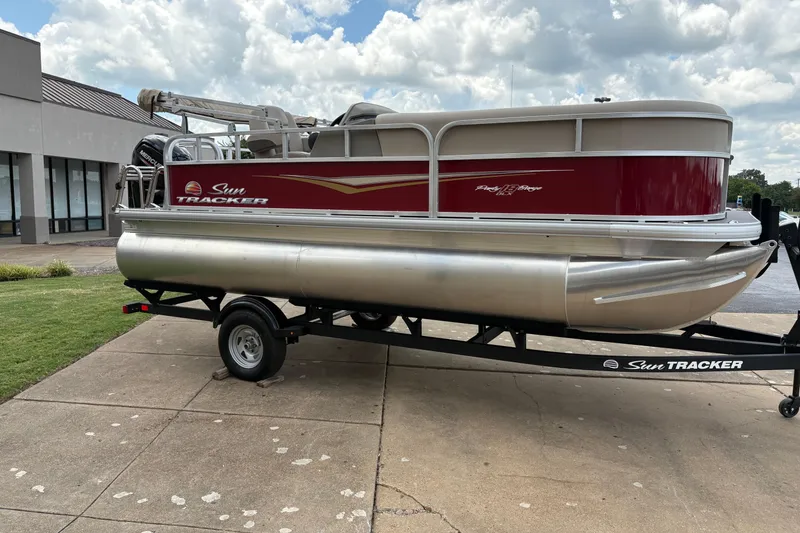 The Image of 2025 Sun Tracker Party Barge 18 DLX pontoon boat on trailer, parked outdoors. - 0
