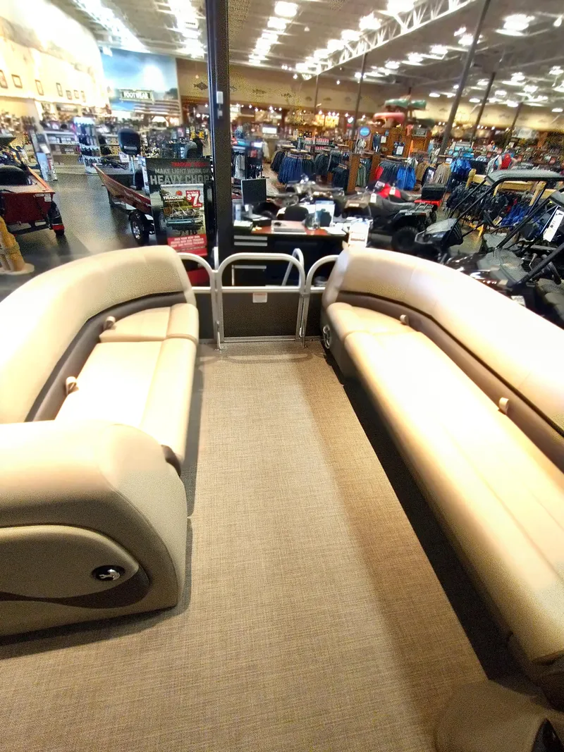 Slide: The Image of 2025 Sun Tracker Party Barge 18 DLX interior with beige seating in showroom. - 14