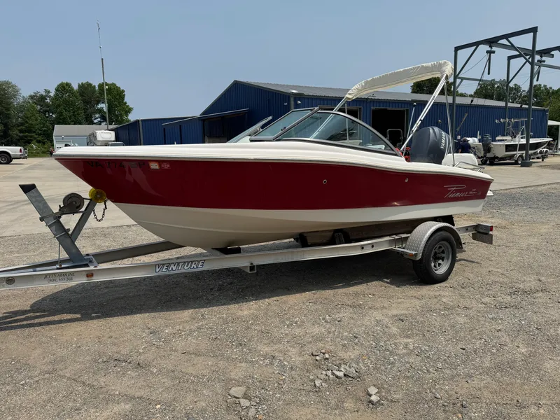 The Image of Red and white 2009 Pioneer 175 Venture boat on trailer in a marina. - 0