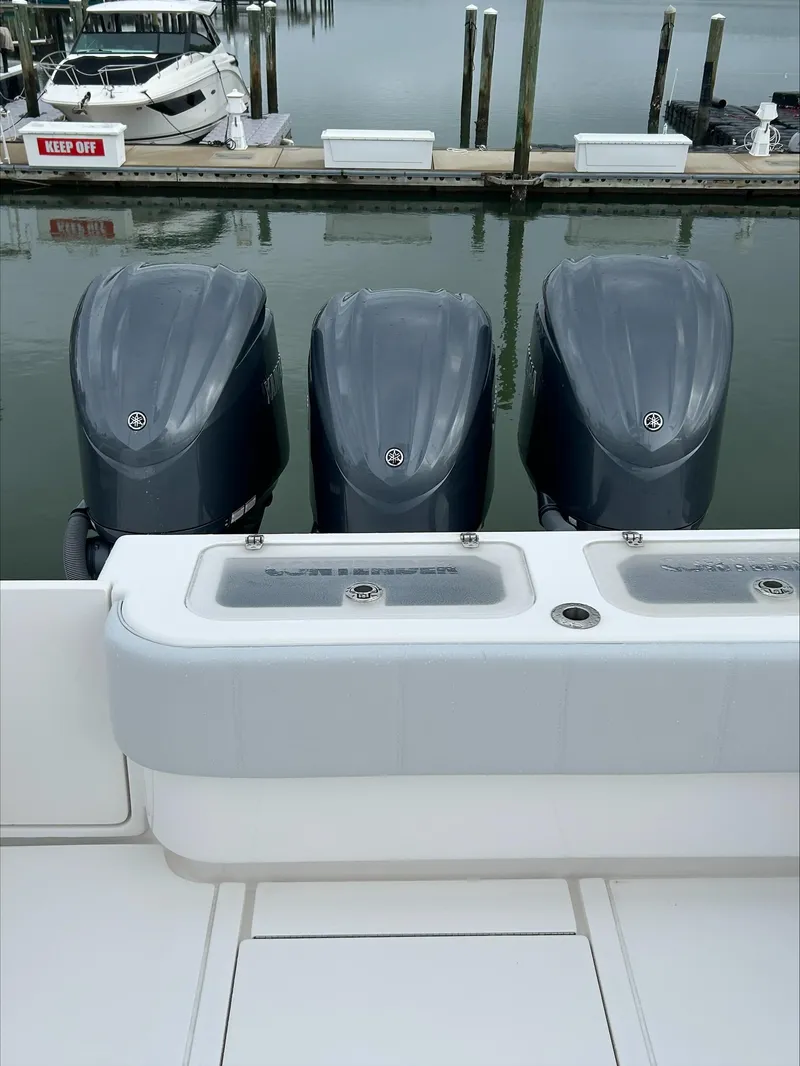 Slide: The Image of 2023 Contender 39 ST boat with triple outboard engines docked at marina. - 1