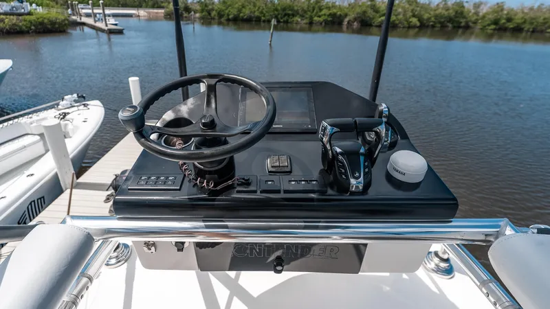 Slide: The Image of 2023 Contender 39 ST boat helm with steering wheel and controls, docked by the water. - 16