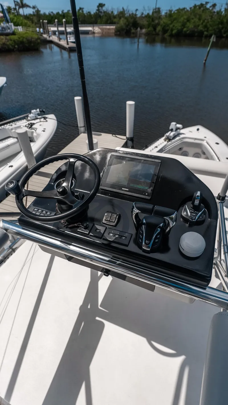 Slide: The Image of 2023 Contender 39 ST boat console with steering wheel and controls, docked by the water. - 17