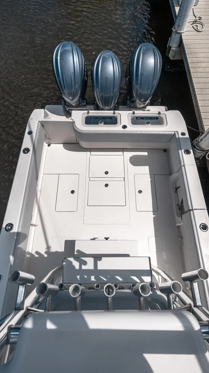 Slide: The Image of 2023 Contender 39 ST boat with triple engines, docked, showcasing spacious deck layout. - 20