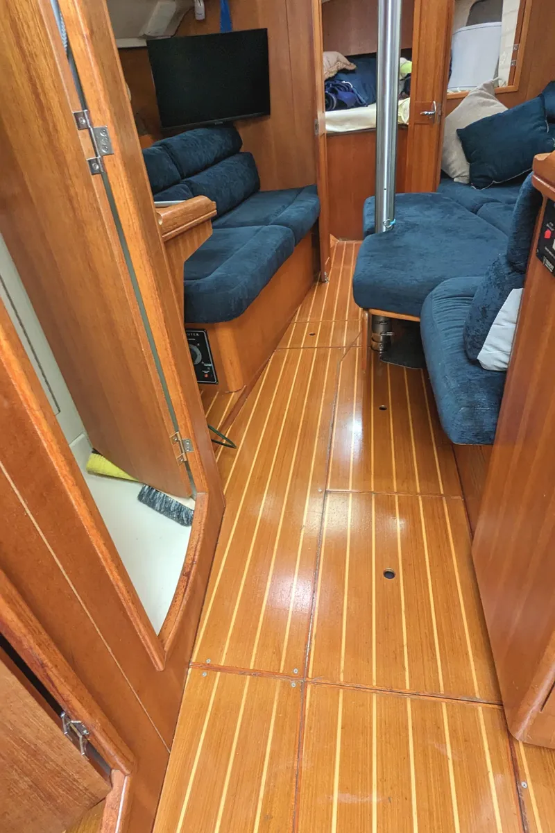Slide: The Image of Interior of 2002 Hunter 326 sailboat with wooden flooring and blue seating. - 16
