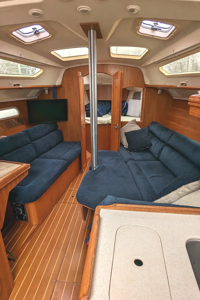 Slide: The Image of Interior of 2002 Hunter 326 sailboat with blue seating and wooden finishes. - 17