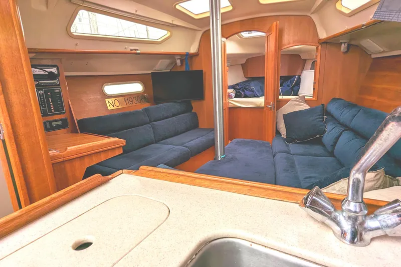 Slide: The Image of Interior of 2002 Hunter 326 sailboat with blue seating and wooden finishes. - 19