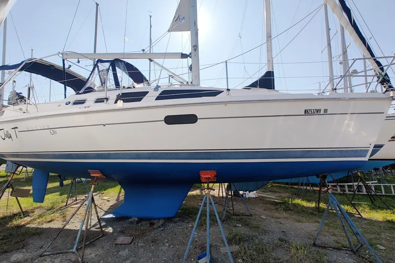 Slide: The Image of 2002 Hunter 326 sailboat on stands, white hull with blue bottom, in a boatyard. - 7