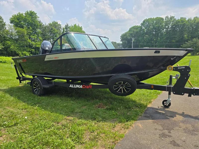 Slide: The Image of 2025 Alumacraft Trophy 185X SP FSX STD CV boat on trailer, parked on grass. - 4