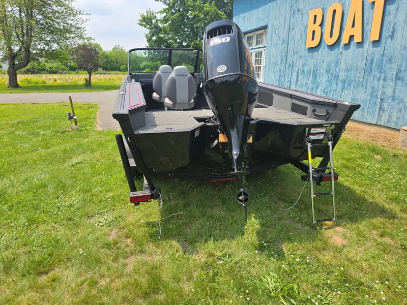 Slide: The Image of 2025 Alumacraft Trophy 185X SP FSX STD CV boat with outboard motor, parked on grass. - 5