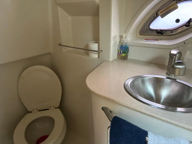 Slide: The Image of 2009 Sea Ray 330 Sundancer bathroom with toilet, sink, and porthole window. - 21