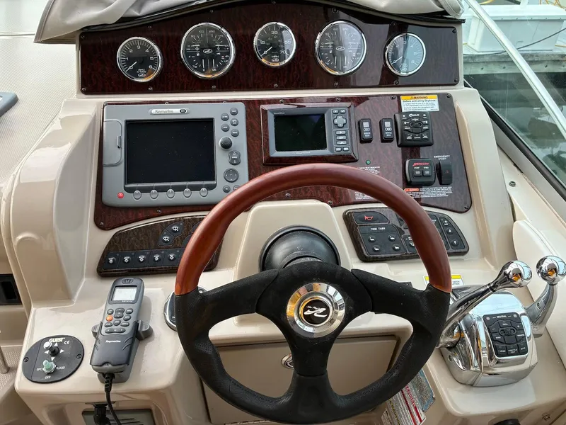 Slide: The Image of 2009 Sea Ray 330 Sundancer helm with gauges, steering wheel, and navigation controls. - 24