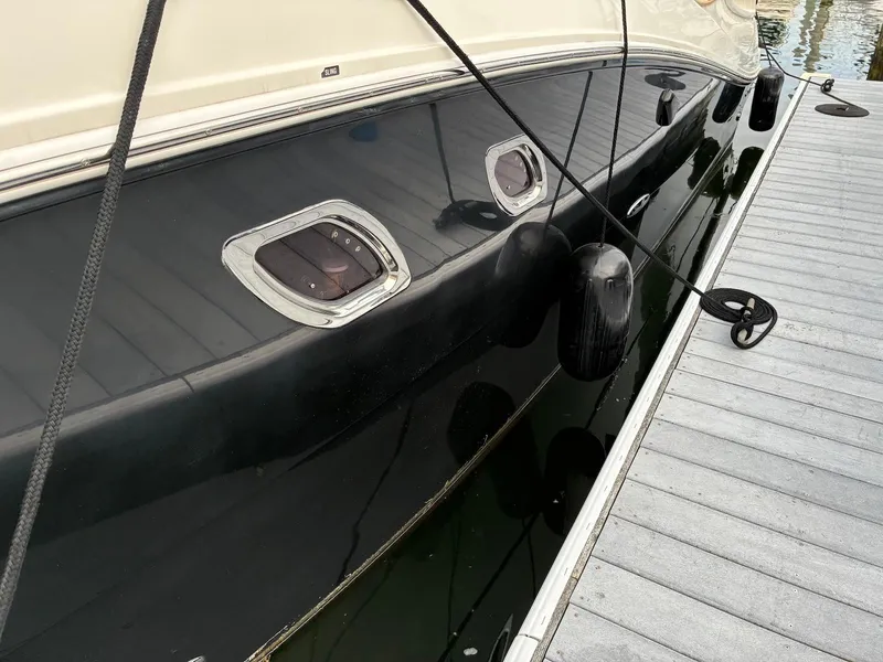 Slide: The Image of 2009 Sea Ray 330 Sundancer docked, showing sleek black hull and portholes. - 31