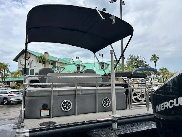 Slide: The Image of 2023 Regency 230 LE3 Sport pontoon boat with canopy, parked outdoors. - 2