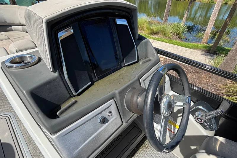 Slide: The Image of 2023 Regency 230 LE3 Sport boat dashboard with steering wheel and control panel. - 4
